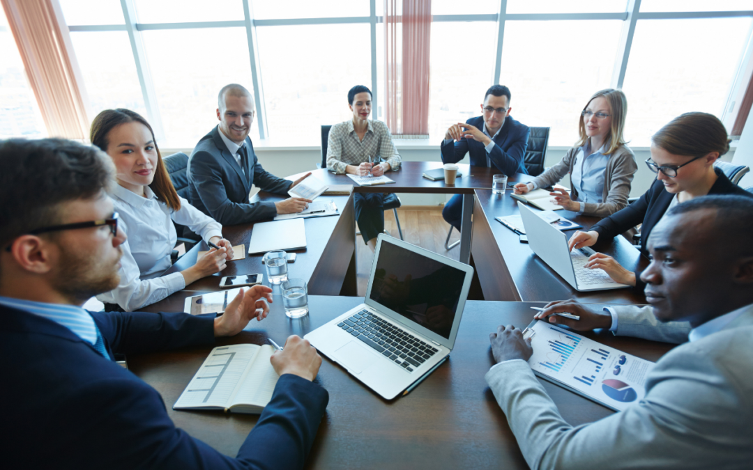 Team of professionals sitting at a table with papers and laptops collaborating.